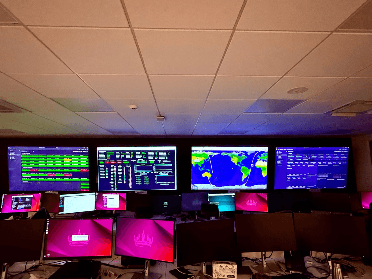 A picture from inside the Pixxel offices, where several desktop monitors displaying Grafana dashboards, as well as larger, wall-mounted dashboards